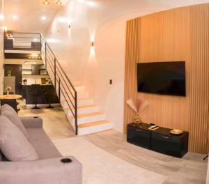 a living room with a couch and a tv and a staircase at River Suite at Luna Negra Suites & Spa in El Castillo de La Fortuna