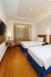 a hotel room with two beds and a television at Grand Orchid Hotel Solo in Solo