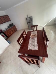 a kitchen with a wooden table with chairs and a refrigerator at Maddox's Place in São Filipe
