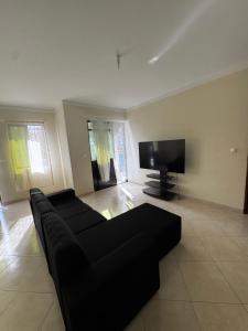 a living room with a black couch and a flat screen tv at Maddox's Place in São Filipe