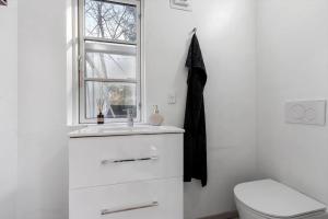 a bathroom with a sink and a toilet and a window at 8880-Grenaa-Lyngtoften-49 in Selkær +18 photos