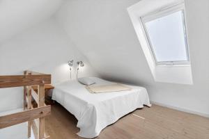 a white bedroom with a bed and a window at 8578-Glesborg-Agterspejlet-13 in Bønnerup Strand