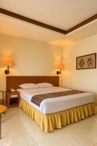 a bedroom with a large bed with a yellow bed skirt at Baron Indah Hotel Solo in Grogol