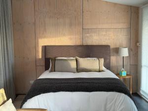 a bedroom with a large bed with a wooden wall at Wombat Pavilion in Yanakie