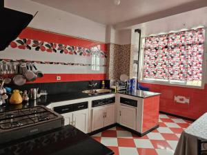 a red and white kitchen with a sink and a stove at Café de Mazagran in Mostaganem