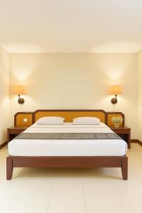 a bedroom with a bed and two lamps on the wall at Baron Indah Hotel Solo in Grogol