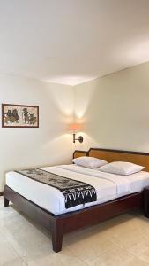 a bedroom with a large bed with white sheets at Baron Indah Hotel Solo in Grogol