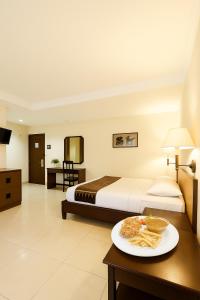 a hotel room with a bed and a plate of food on a table at Baron Indah Hotel Solo in Grogol +2 photos
