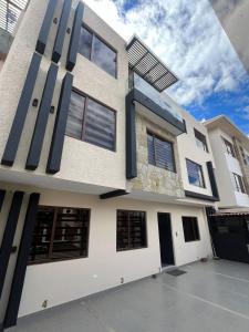 a white house with black doors and windows at Casa Central in Cuenca
