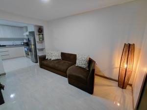 a living room with a brown couch and a kitchen at Casa Central in Cuenca