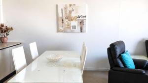 a white dining room table and a black chair at Amazing Views, Walk Everywhere! in Caloundra