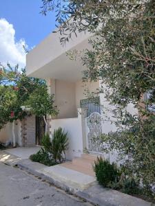 a white house with a gate and trees at Dar Si Lamin 2 in Kelibia