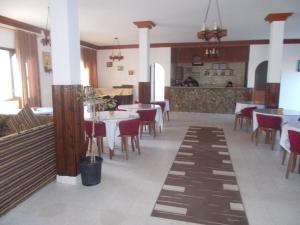 a dining room with tables and chairs and a kitchen at Montazah Residence in Dar el Koudia