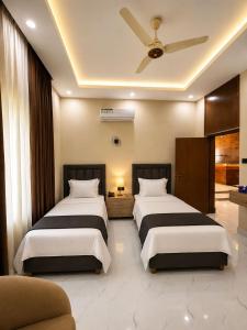 a bedroom with two beds and a ceiling fan at Hotel Regent DHA in Karachi +17 photos