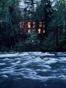 a house in the woods next to a river at Roaring River Lodge Riverfront Fire pit EV Plug in Rhododendron