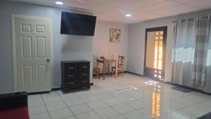 a living room with a tv on the wall and a table at mi casa tropical in Hacienda Santa Clara