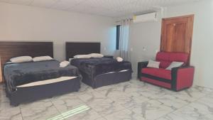 a bedroom with two beds and a couch and a chair at mi casa tropical in Hacienda Santa Clara