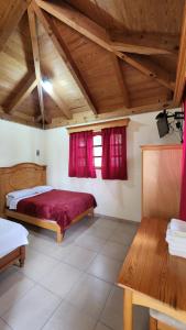 a bedroom with a red bed and a wooden ceiling at Cabaña Oasis Ixmiquilpan in Ixmiquilpan