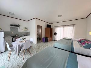 a bedroom with a bed and a table and a kitchen at Cabañas Honu Nui Inn in Hanga Roa