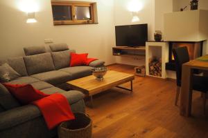 a living room with a couch and a tv and a table at Apartment Smaragdblick Wildkogel in Bramberg am Wildkogel