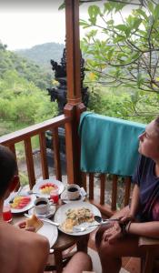 a group of people sitting at a table with food at Nora Cottage Natural in Batununggul +4 photos