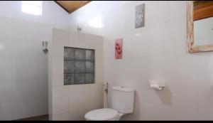 a white bathroom with a toilet and a window at Nora Cottage Natural in Batununggul