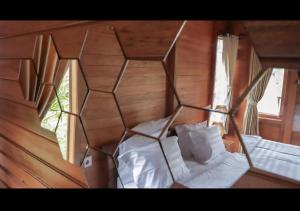 a bedroom with a wooden wall with a bed and two windows at Nora Cottage Natural in Batununggul