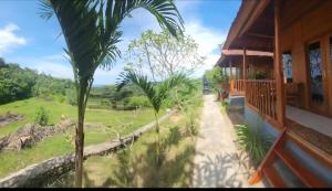 a house with a palm tree in front of it at Nora Cottage Natural in Batununggul