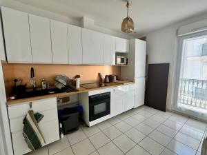 a small kitchen with white cabinets and a window at The Rave in Sète