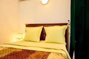 a bedroom with a bed with yellow sheets and pillows at BJ House in Douala