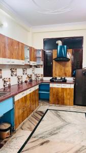 a kitchen with wooden cabinets and a black refrigerator at Kamlesh Niwas in Rishīkesh