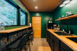 a kitchen with green walls and a bar with stools at The Taoist 5min to Gorge with Private Cliffs in Rogers