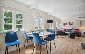a living room with a dining table and blue chairs at AE329-Aeroskobing-Oster-Bregninge-24 in Ærøskøbing