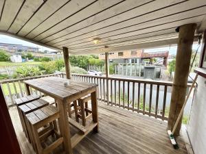 a wooden deck with a table and bench on a balcony at Large Bach in Raglan central in Raglan +10 photos