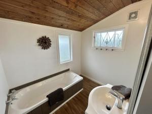 a bathroom with a bath tub and a sink at Large Bach in Raglan central in Raglan