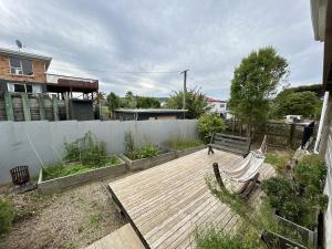 a wooden deck with a bench in a backyard at Large Bach in Raglan central in Raglan