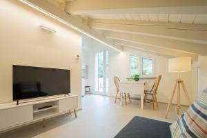 a living room with a television and a table with chairs at Ulivo, Relax a due passi dal mare in San Lazzaro