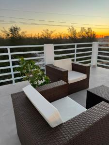 a balcony with two wicker chairs and a table at Pousada 8 Mares in Arraial do Cabo