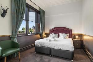 a bedroom with a bed and a green chair at Imperial Hotel Paddington in Sydney