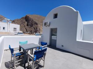 a patio with blue chairs and a table on a building at Perissa Economy Rooms in Santorini