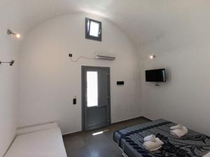 a bedroom with a bed and a window and a door at Perissa Economy Rooms in Santorini
