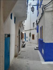 an alley with blue and white buildings and a car at San Marcelo De Tangier in Tangier