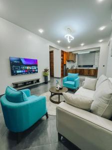 a living room with a couch and chairs and a tv at Zabibu Collection in Arusha