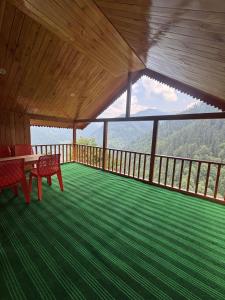 a room with a table and chairs on a balcony at the jibhi nest cottage in Mandi