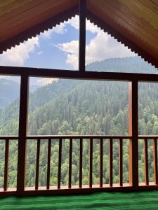 a view of the mountains from a room with a window at the jibhi nest cottage in Mandi +4 photos
