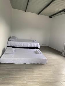 two beds in a white room with a wooden floor at Ambar Apartahotel - Clasico in San Luis