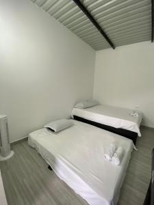 two beds in a room with white walls and wood floors at Ambar Apartahotel - Clasico in San Luis