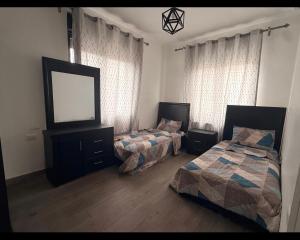 a bedroom with two beds and a television in it at Casablanca chalet in Umm Nūwārah +3 photos