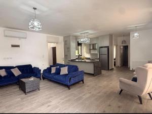 a living room with blue couches and a kitchen at Casablanca chalet in Umm Nūwārah