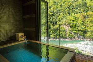 a bath tub with a view of a river at Enraku in Kurobe